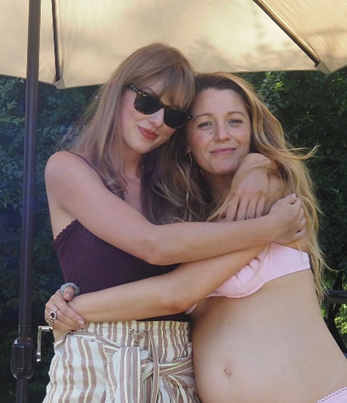 Two women embracing outdoors under an umbrella, highlighting Blake Lively and Ryan Reynolds's texts about Justin Baldoni case.