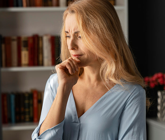 Woman looking upset and deep in thought, struggling to contain her rage over a teacher ignoring her daughter’s emergency.