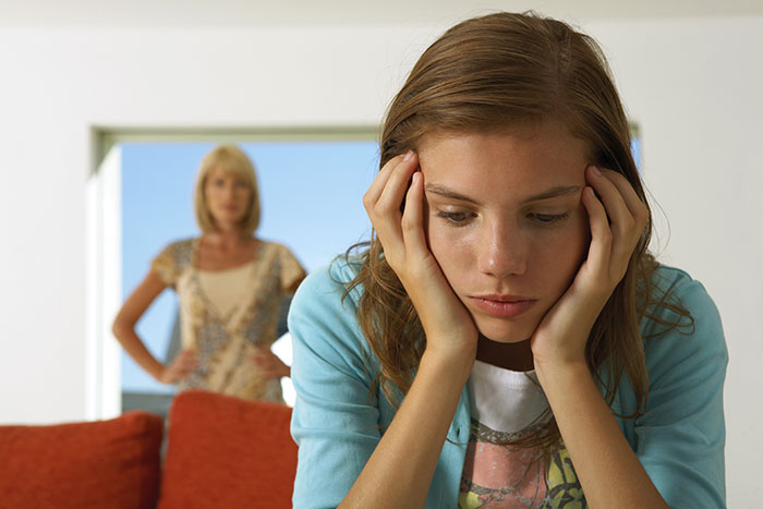 Teen girl looking upset while older woman stands in background, highlighting tension and crushed dreams during Christmas. Teen girl looking upset while older woman stands in background, highlighting tension and crushed dreams during Christmas.