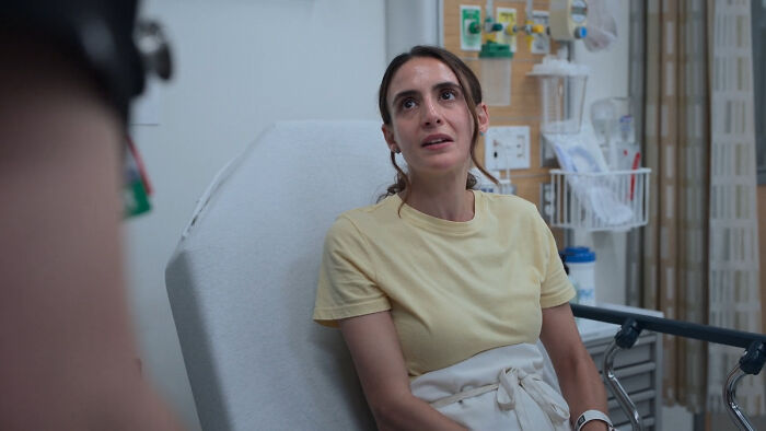 Young woman in hospital bed, discussing concerns about MRSA and hospital-acquired infections with medical staff.