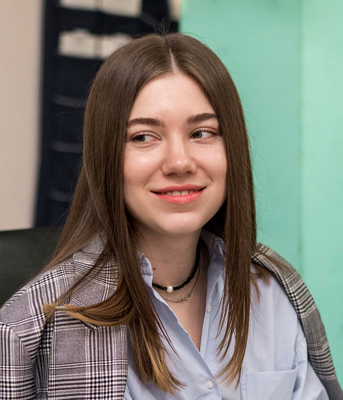 Young woman in a blazer and shirt smiling confidently during a job interview with recruiters about candidate mistakes.