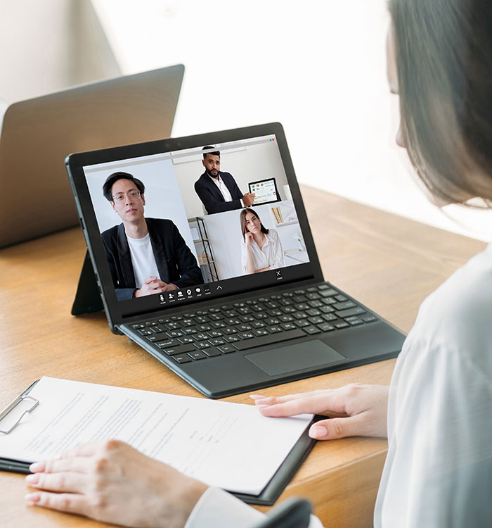 Woman attending a virtual job interview on laptop with recruiters assessing job candidates for hiring decisions.