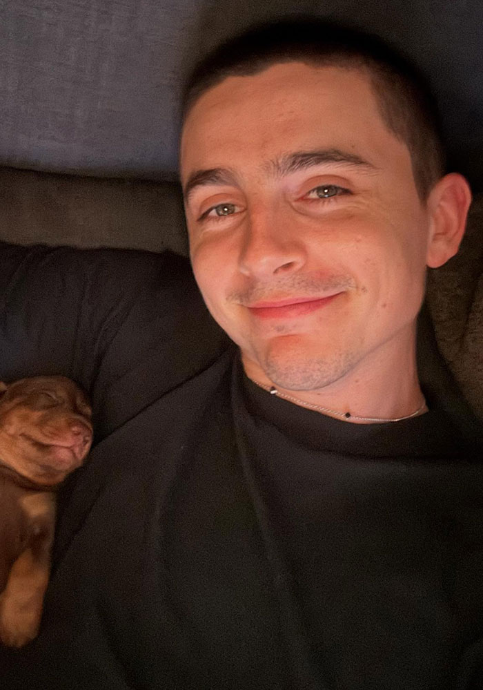 Timoth&eacute;e Chalamet smiling in a selfie while lying down next to a sleeping puppy, related to Golden Globes fight news.