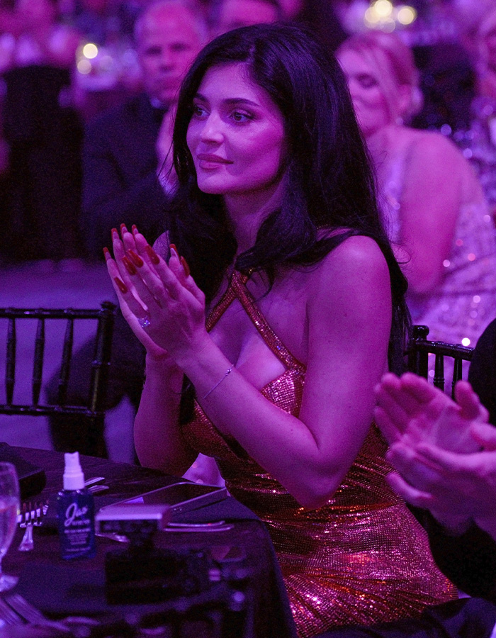 Kylie Jenner wearing a sparkling dress and clapping at an event, sparking buzz with Timoth&eacute;e Chalamet outing.