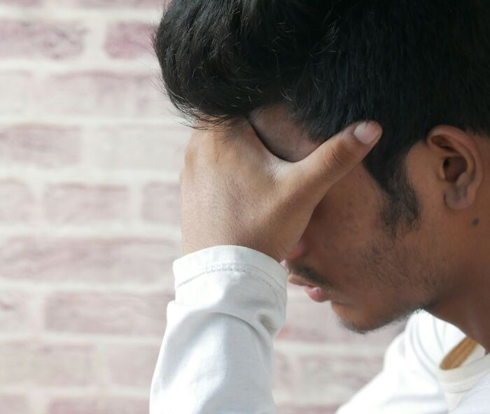 Man in white shirt holding his head in frustration, reflecting on wedding moments and relationship doubts.