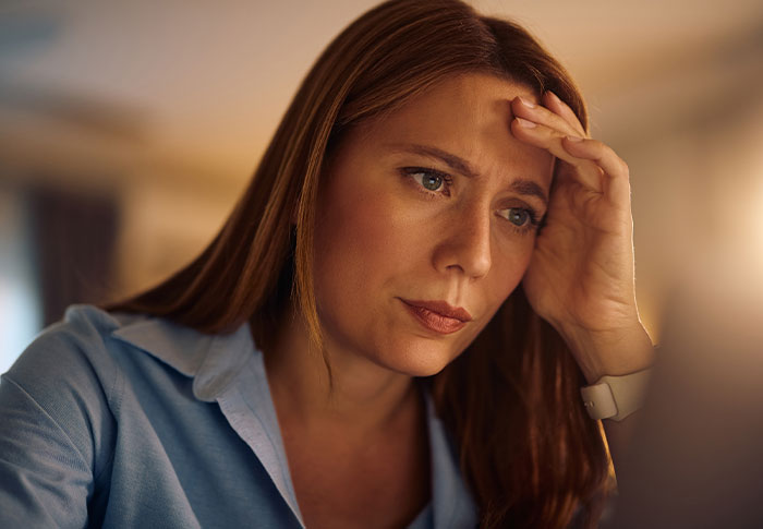 Worried mother sitting at a desk, contemplating the school request to make her twins less similar for easier distinction. Worried mother sitting at a desk, contemplating the school request to make her twins less similar for easier distinction.