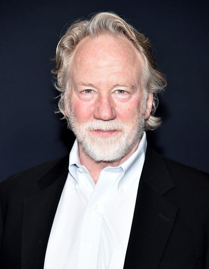 West Wing star Timothy Busfield in a black jacket and white shirt against a dark background for US Marshals manhunt coverage.