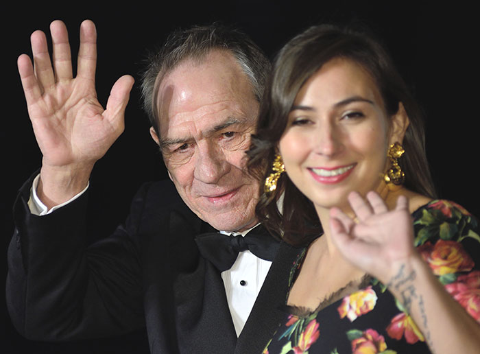 Tommy Lee Jones and woman waving at event, related to horrifying new twist in daughter hotel case.