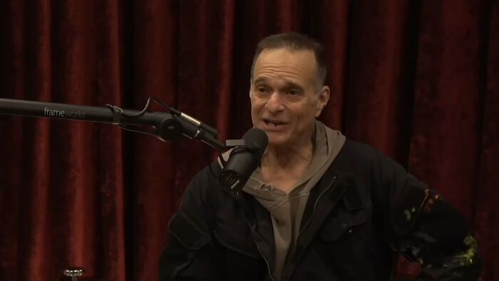 Man speaking into microphone during a podcast recording, related to people meeting their idols and regret stories.