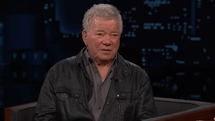 Older man in a dark jacket speaking during a late night talk show, capturing a moment of meeting idols in real life.