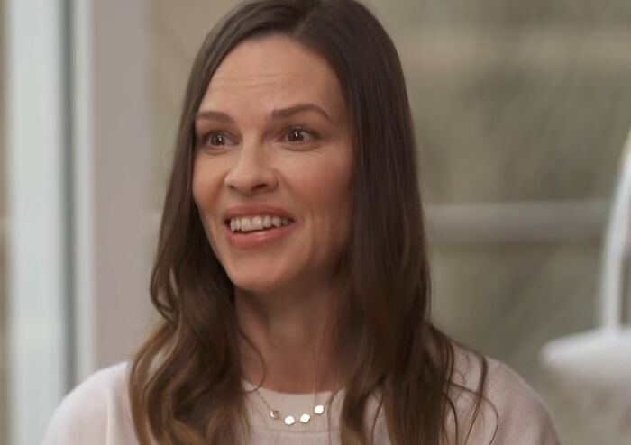 Smiling woman with long brown hair in a light sweater, sharing a story about meeting idols and regret experiences online.