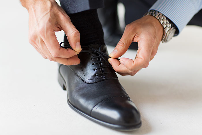 Man tying black dress shoe laces, representing the moment attraction ended due to a weird ick women experienced.