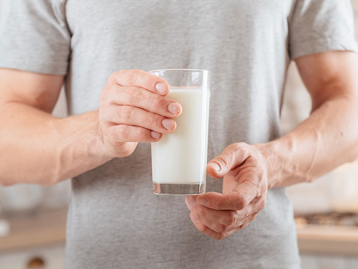 Man holding a glass of milk, illustrating a weird ick moment related to attraction ending for women.