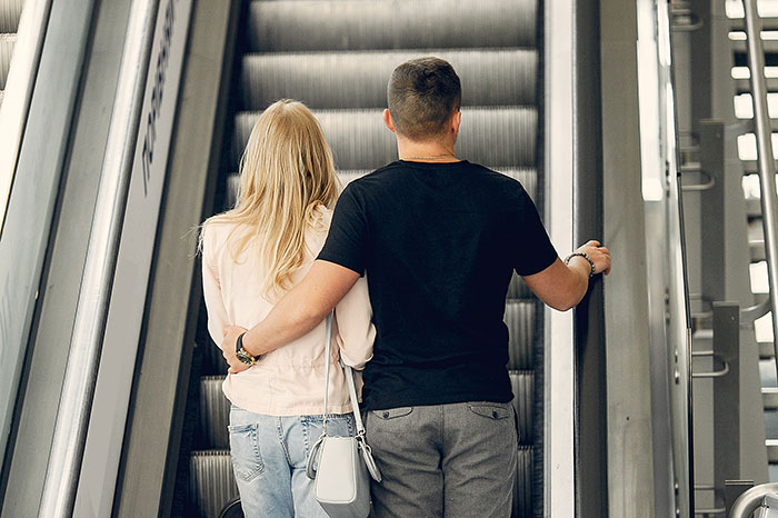 Couple standing close on escalator, illustrating the moment attraction ended due to a weird ick one partner experienced.