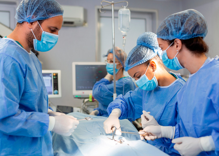 Surgeons performing a procedure in an operating room, illustrating the use of donated lifeless bodies for BBLs and breast implants.