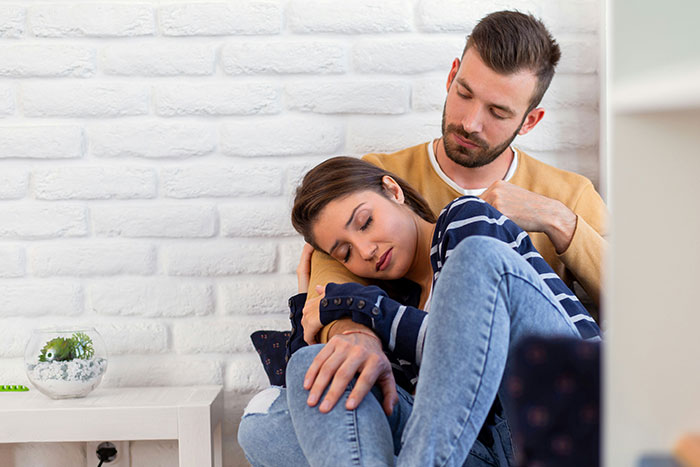 Man looking devastated while sitting with wife, illustrating emotional impact of infidelity after snooping on conversation.