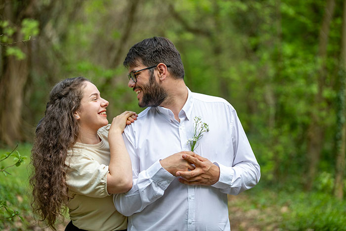 Man and woman smiling outdoors in a forest, highlighting emotions related to infidelity and relationship trust issues.