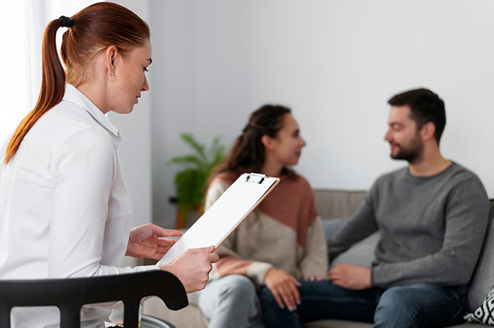Couple in therapy session discussing relationship issues with counselor amid man debating divorce over validation seeking.