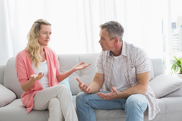 Man and woman sitting on couch, having an intense discussion about validation seeking and debating divorce.