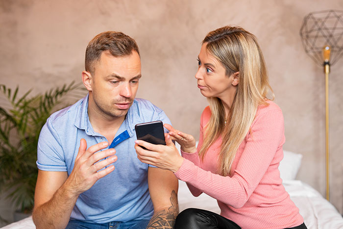 Man debating divorce with wife showing validation seeking behavior while holding a phone during a serious conversation.