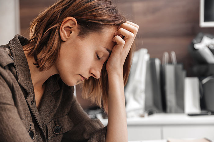 Woman looking stressed and frustrated while sitting indoors, reflecting annoyance about her SIL situation.
