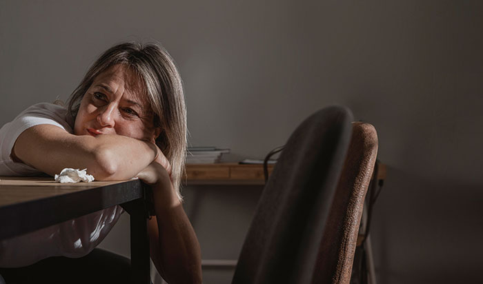Woman looking upset and tired while complaining about sister-in-law, husband appearing annoyed in a dimly lit room.