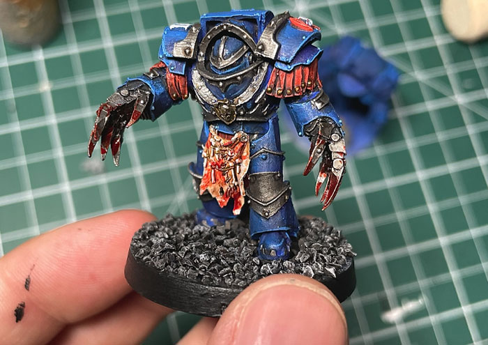 Hand-painted Star Wars figure held over a cutting mat, highlighting detailed miniature craftsmanship and hobby work.