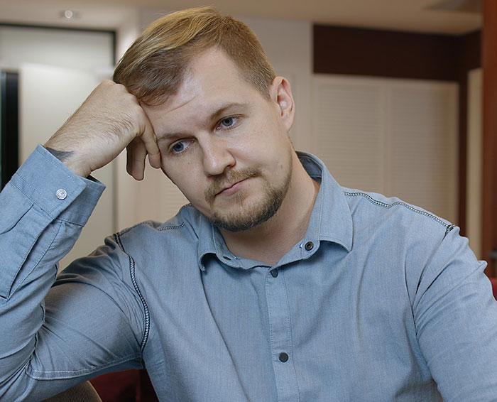 Husband in a blue shirt looking thoughtful and bothered while sitting indoors, reflecting on his wife's choice at home Husband in a blue shirt looking thoughtful and bothered while sitting indoors, reflecting on his wife's choice at home