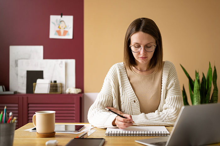 Mom studying at home while dad struggles to keep toddler away to help her focus on work and studying.