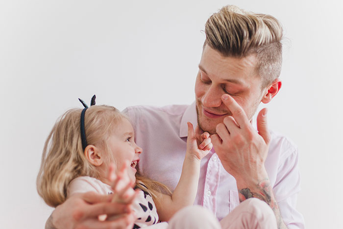 Dad struggling to keep toddler away from mom so she can study, showing playful interaction and family bonding moments. Dad struggling to keep toddler away from mom so she can study, showing playful interaction and family bonding moments.