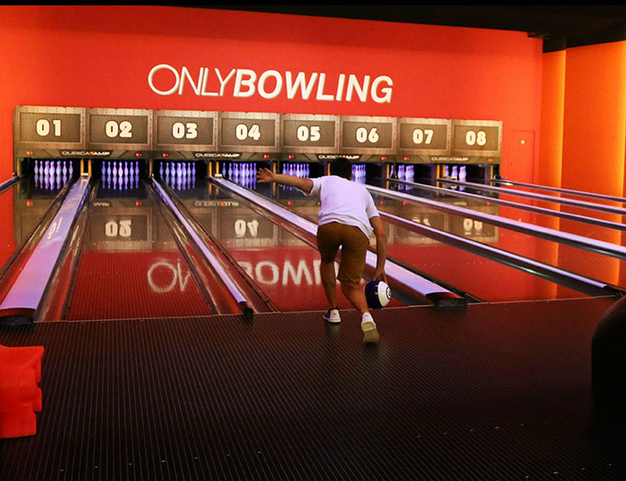 Person bowling in an alley with bright orange walls, capturing a moment people witnessed something weird.
