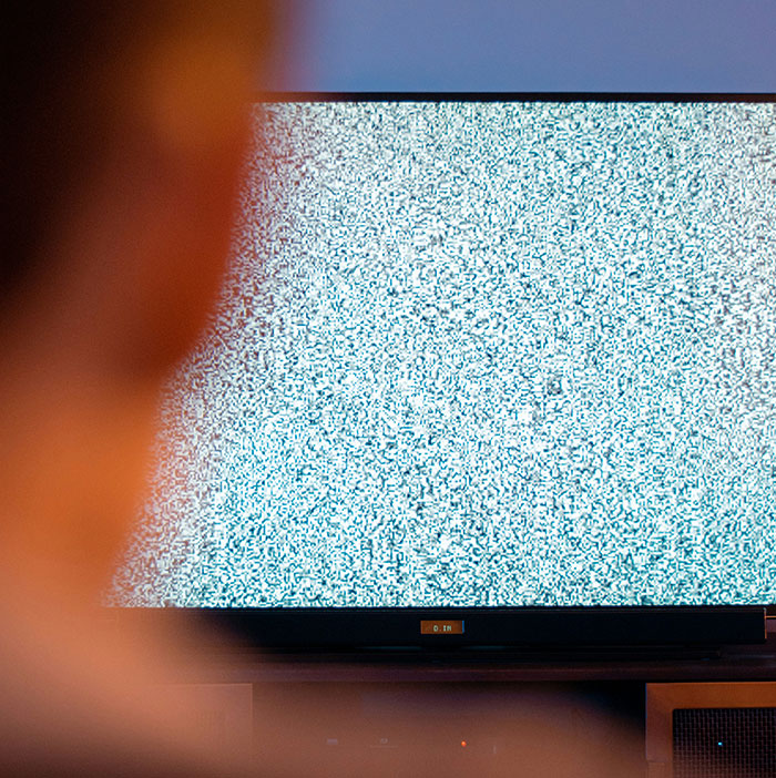 Person watching TV with static screen, symbolizing weird moments people witnessed they still can't explain.
