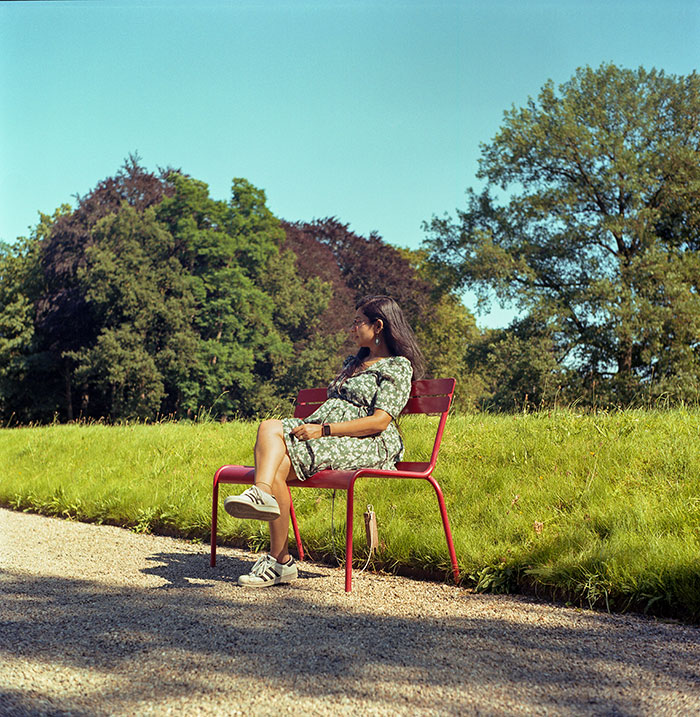 Woman sitting on a red bench outdoors in a park, experiencing a moment people witnessed so weird they can't explain.