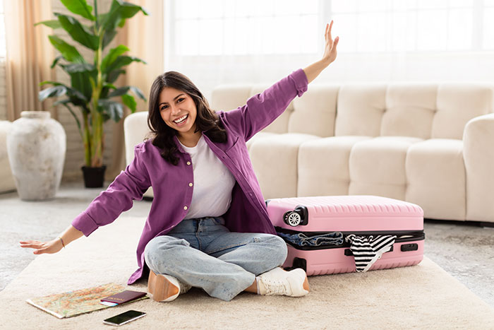 Young woman with suitcase sitting on floor, excited and surprised after proposal and arranged marriage in India.