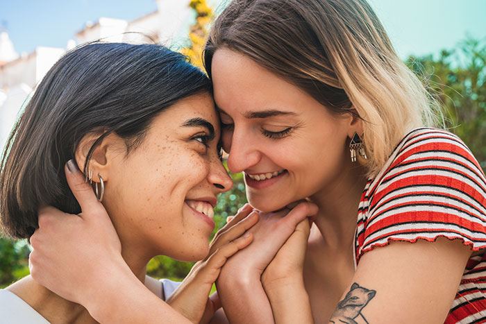 Two women share a joyful moment embracing outdoors, highlighting themes of proposals and arranged marriage in India. Two women share a joyful moment embracing outdoors, highlighting themes of proposals and arranged marriage in India.