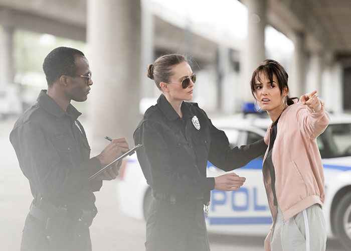 Two police officers questioning a distressed woman about a fiancée’s obsession with her bully stalking issue outdoors. Two police officers questioning a distressed woman about a fiancée’s obsession with her bully stalking issue outdoors.