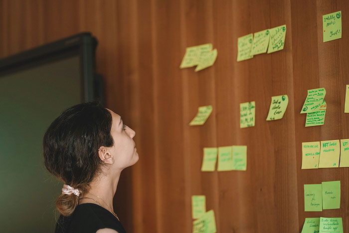 Woman analyzing sticky notes on a wooden wall, focused on matching relationship energy with her boyfriend. Woman analyzing sticky notes on a wooden wall, focused on matching relationship energy with her boyfriend.