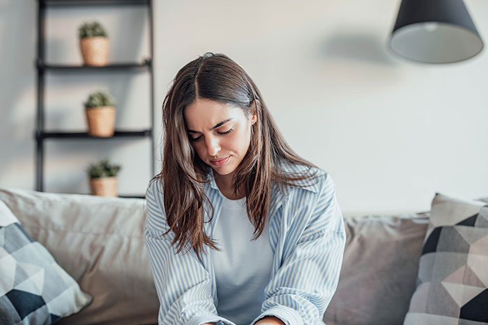 Young woman matching relationship energy with her boyfriend, sitting thoughtfully on a couch indoors. Young woman matching relationship energy with her boyfriend, sitting thoughtfully on a couch indoors.