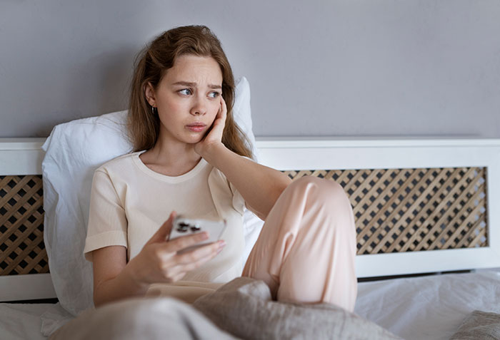 Young woman looking worried and holding a phone, reflecting on a complicated four-year relationship and mistress situation.