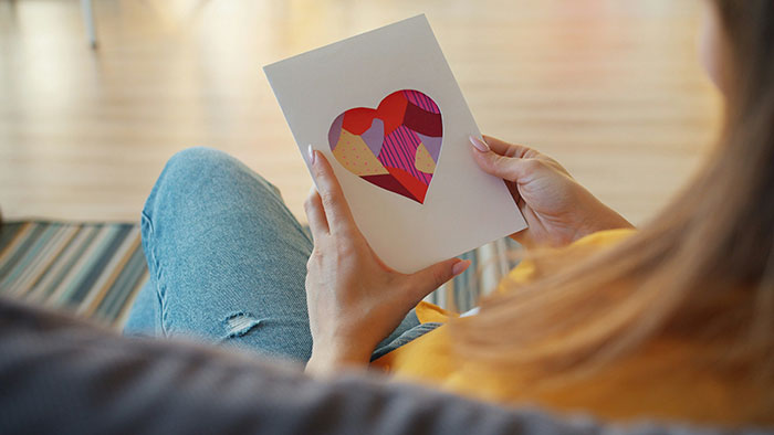 Woman holding a card with a heart, reflecting on a relationship where she was unknowingly the mistress.