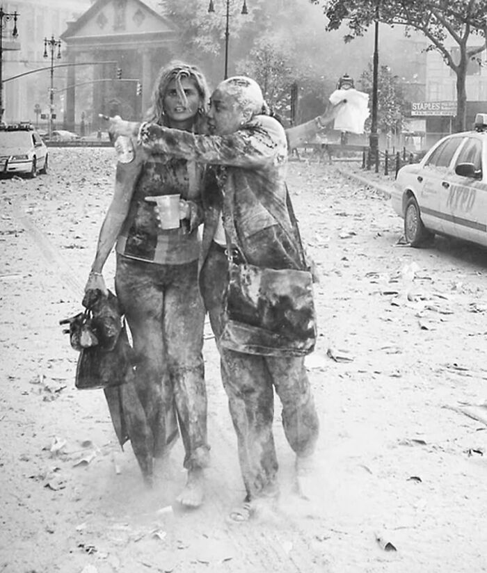 Two dust-covered women walk through a city street showing the sad and sometimes horrific history of humanity.