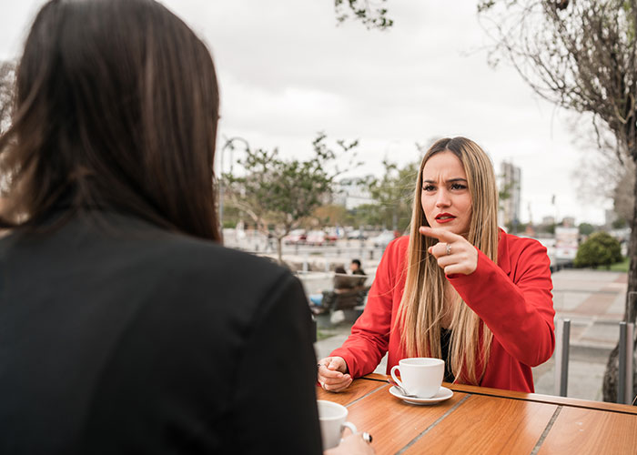 Woman in a red blazer refusing to give free advice to friends, revealing her true colors during a serious outdoor conversation.
