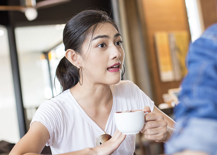 Young woman holding a cup, expressing frustration while discussing her new career and setting boundaries with friends.
