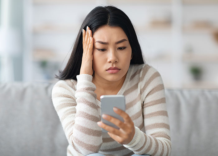 Young woman concerned while looking at her phone, reflecting on career boundaries and true colors of friends.