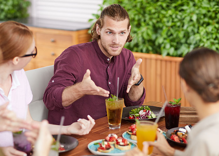 Man explaining with hand gestures at a table, symbolizing woman refusing to risk new career for free advice.