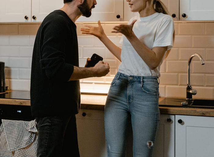 Woman and boyfriend arguing in kitchen after he eats food she saved for their kids, illustrating love is a verb conflict. Woman and boyfriend arguing in kitchen after he eats food she saved for their kids, illustrating love is a verb conflict.
