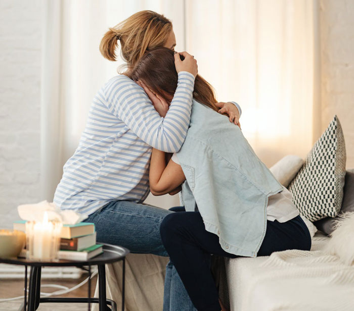 Woman comforting upset girl on couch in cozy home, reflecting themes of love and hardship in family life. Woman comforting upset girl on couch in cozy home, reflecting themes of love and hardship in family life.