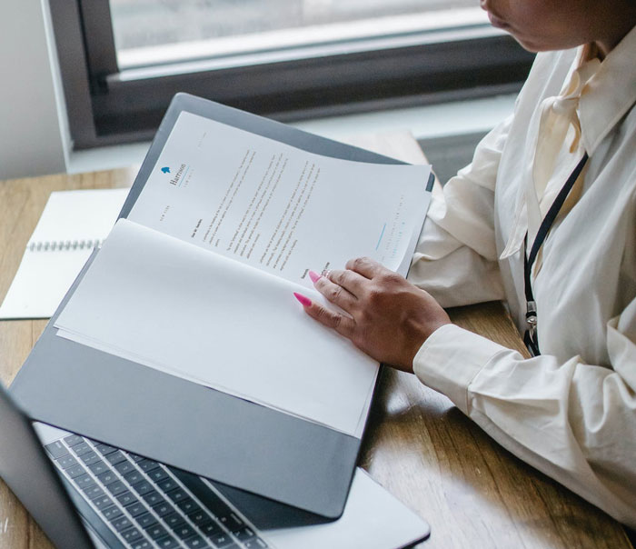 Woman reviewing documents at a desk near a laptop, representing love is a verb and relationship struggles with food savings. Woman reviewing documents at a desk near a laptop, representing love is a verb and relationship struggles with food savings.