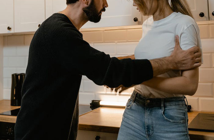 Man and woman in kitchen having tense argument, highlighting love is a verb and relationship conflict over food saved for kids. Man and woman in kitchen having tense argument, highlighting love is a verb and relationship conflict over food saved for kids.