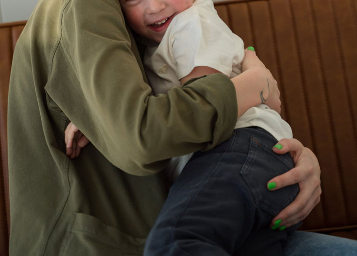 Woman with green nail polish hugging child, illustrating love is a verb and family care despite struggles. Woman with green nail polish hugging child, illustrating love is a verb and family care despite struggles.